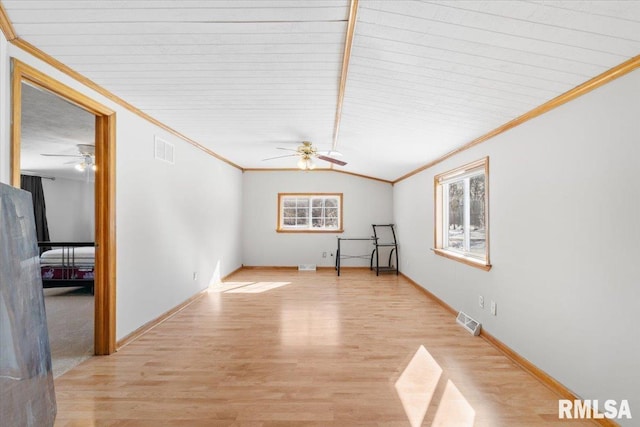 empty room with ceiling fan, vaulted ceiling, crown molding, and light hardwood / wood-style floors