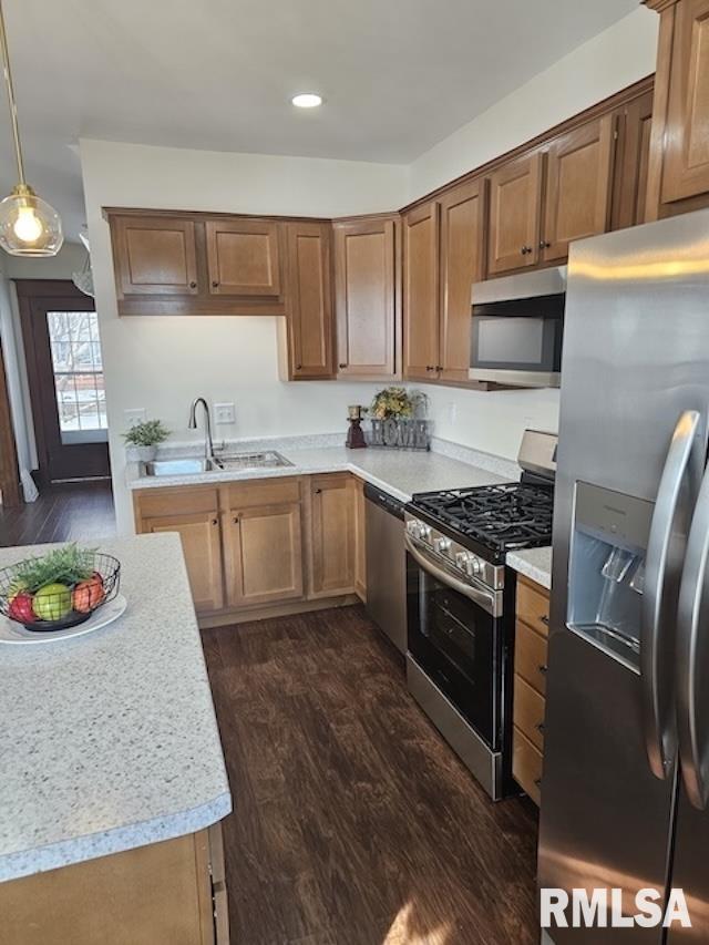 kitchen featuring sink, hanging light fixtures, stainless steel appliances, and dark hardwood / wood-style flooring