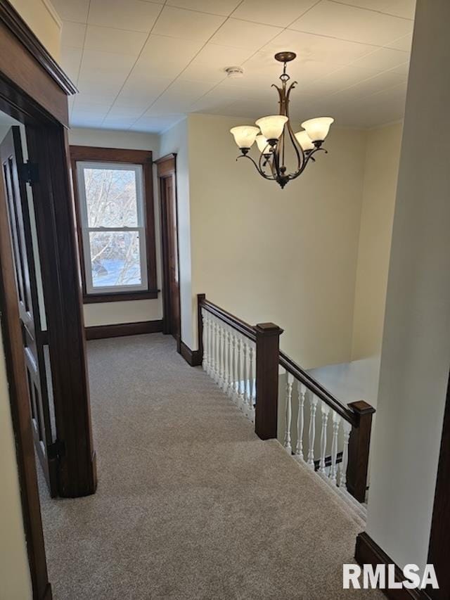 hallway featuring carpet flooring and a chandelier