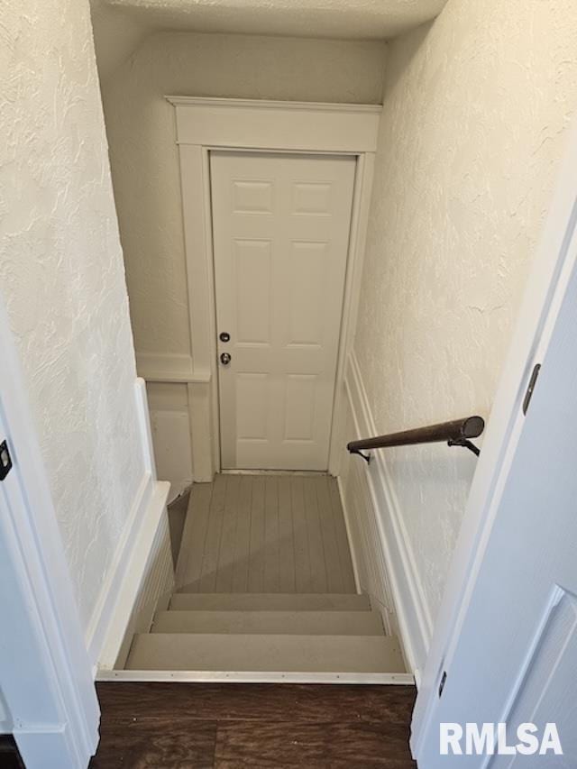 staircase featuring hardwood / wood-style floors and a textured ceiling