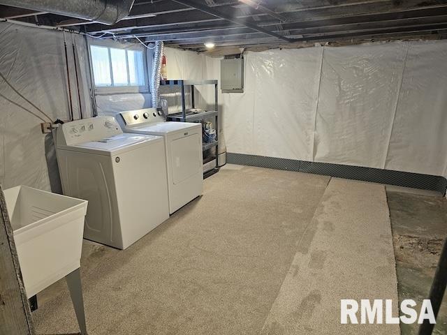 clothes washing area featuring electric panel, washing machine and dryer, and sink