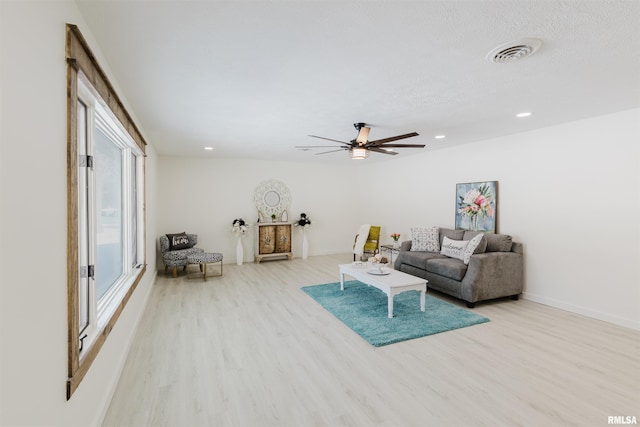 living room featuring baseboards, light wood-style flooring, visible vents, and recessed lighting