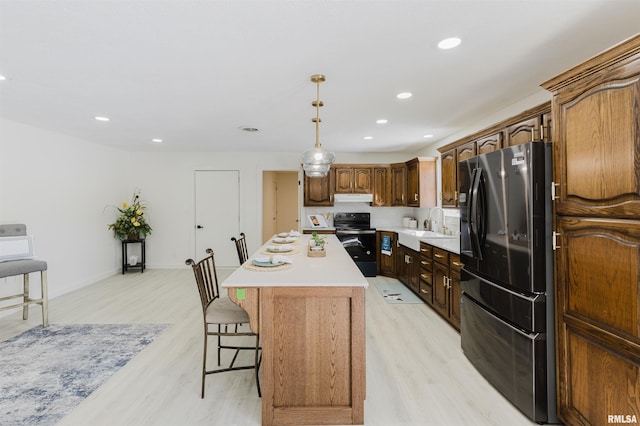 kitchen with electric range, a sink, light countertops, freestanding refrigerator, and a center island