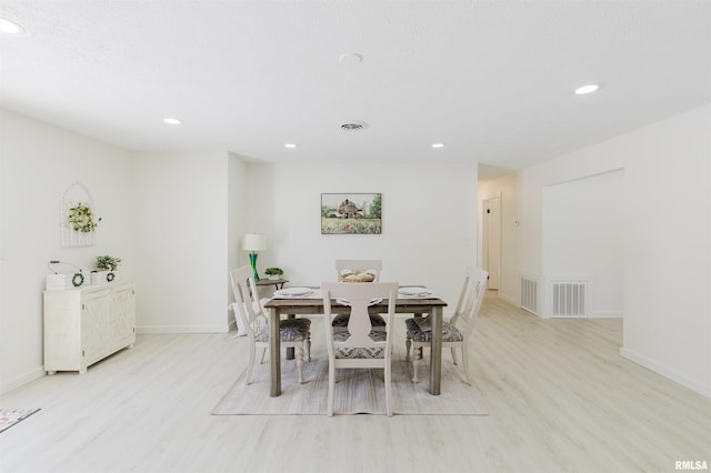 dining area featuring light wood finished floors, visible vents, and baseboards