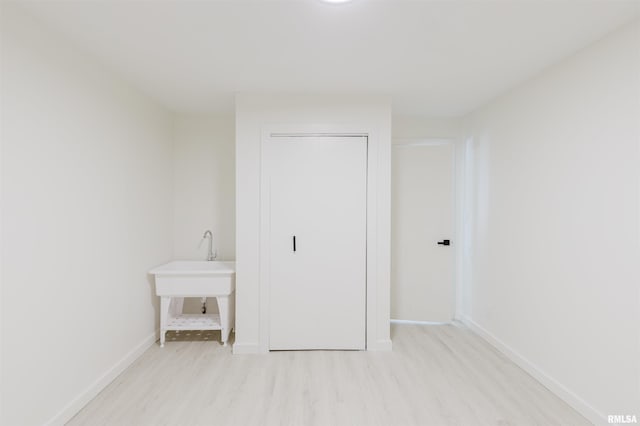 unfurnished bedroom featuring light wood finished floors, baseboards, and a closet