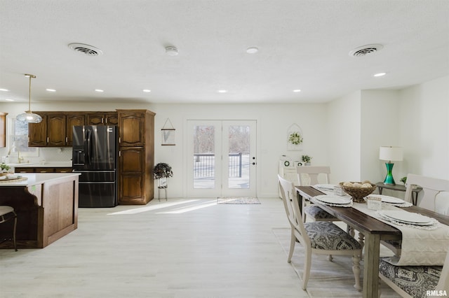 dining area with a textured ceiling, light wood finished floors, visible vents, and recessed lighting