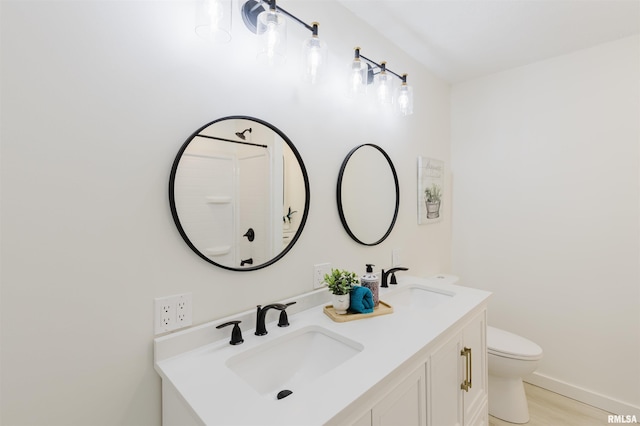 bathroom featuring wood finished floors, a sink, toilet, and double vanity