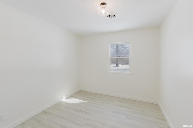 spare room featuring light wood-type flooring, visible vents, and baseboards