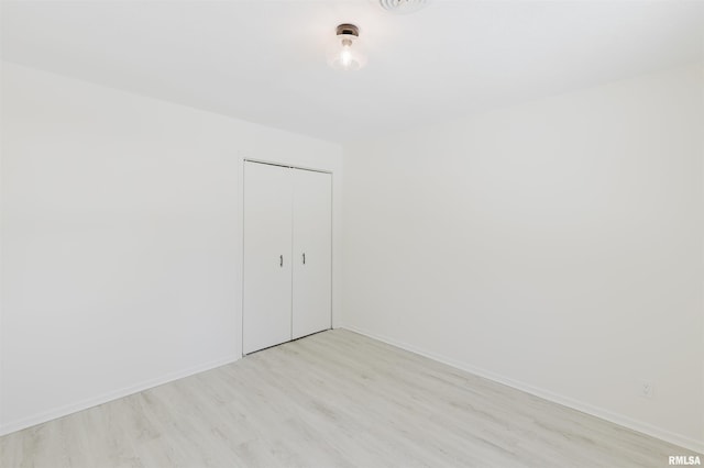 unfurnished room with light wood-type flooring and baseboards