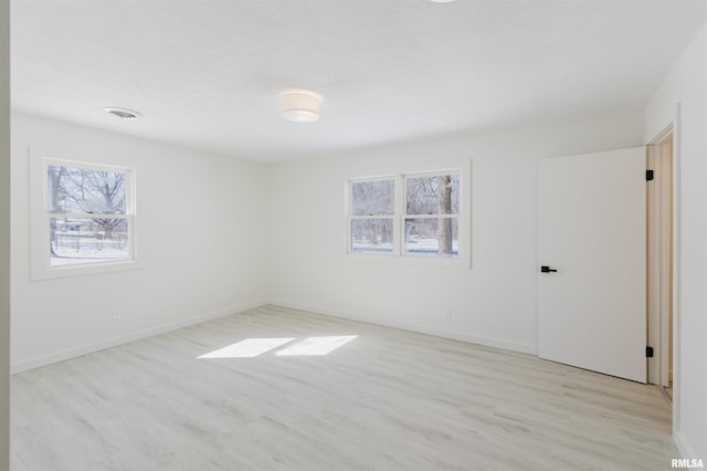 empty room featuring baseboards, visible vents, and light wood-style floors