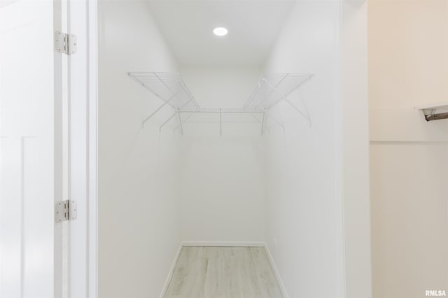 walk in closet with light wood finished floors