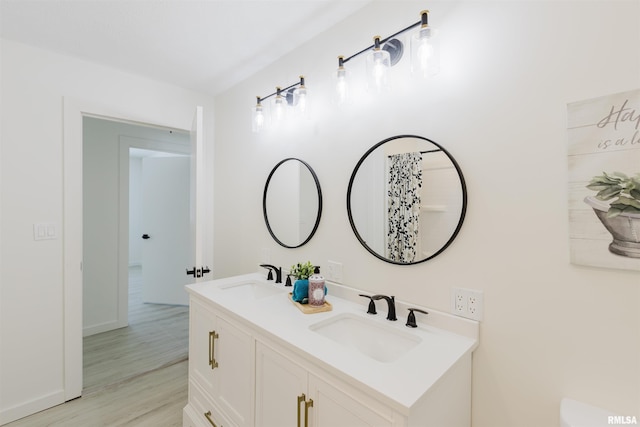 bathroom with double vanity, a sink, and wood finished floors