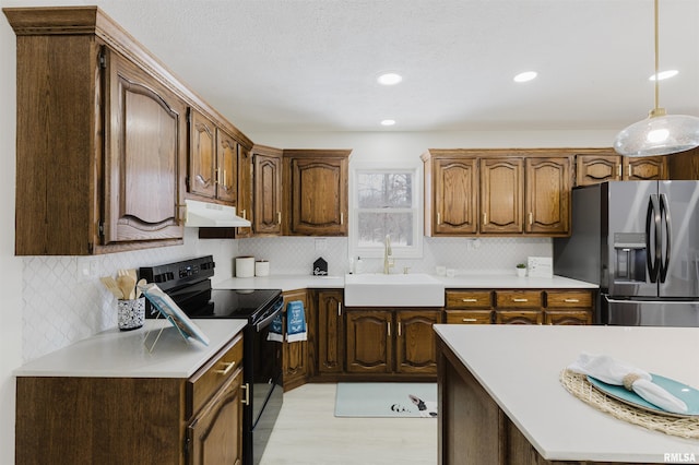 kitchen with light countertops, black range with electric stovetop, a sink, under cabinet range hood, and stainless steel fridge with ice dispenser