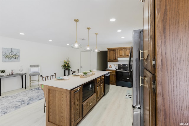 kitchen with a center island, hanging light fixtures, under cabinet range hood, light countertops, and black appliances