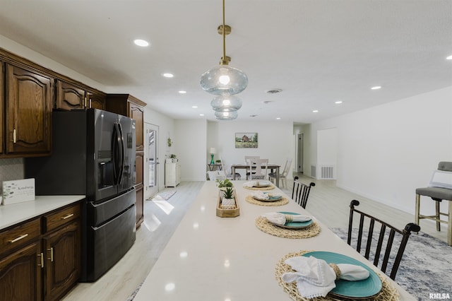 kitchen featuring light countertops, hanging light fixtures, visible vents, dark brown cabinets, and stainless steel fridge