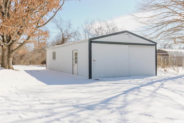 snow covered structure with an outbuilding