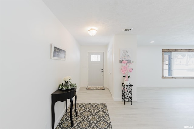 foyer featuring light wood finished floors, visible vents, and baseboards