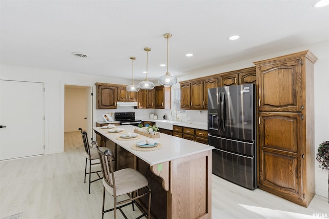 kitchen with a center island, visible vents, light countertops, electric range, and stainless steel fridge with ice dispenser