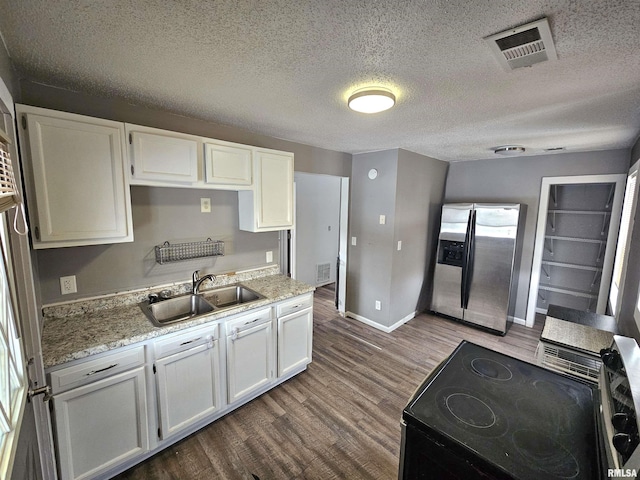 kitchen with stainless steel refrigerator with ice dispenser, hardwood / wood-style floors, black electric range, sink, and white cabinetry