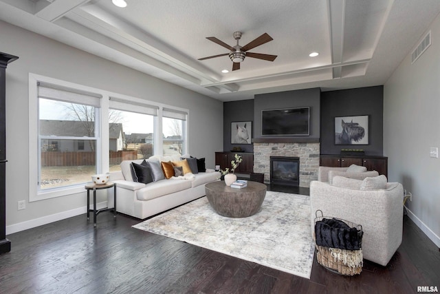 living room with baseboards, visible vents, a raised ceiling, dark wood-style floors, and a fireplace