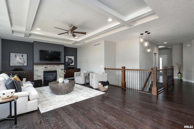 living area with visible vents, a fireplace, a textured ceiling, and wood finished floors