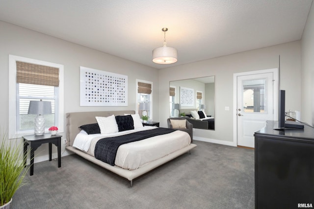 bedroom featuring dark carpet, a textured ceiling, and baseboards