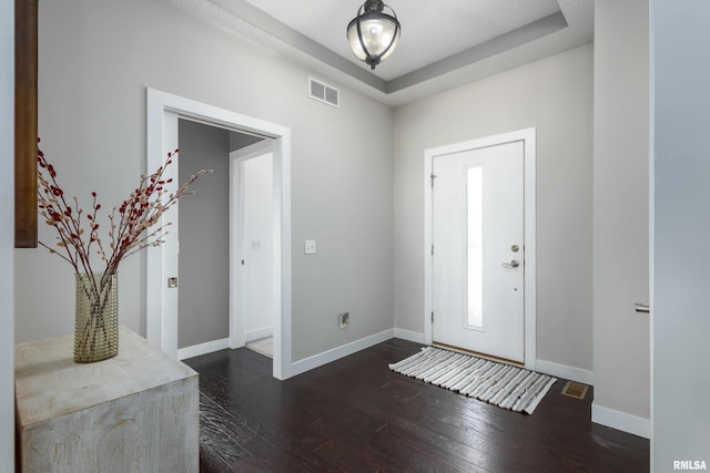 foyer entrance with baseboards, visible vents, and dark wood-style flooring