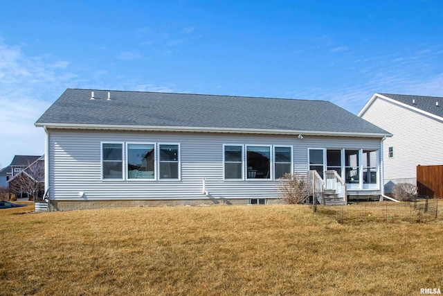 rear view of house featuring a sunroom, a shingled roof, and a yard