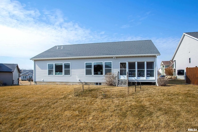 back of house featuring a yard, a shingled roof, fence, and a sunroom