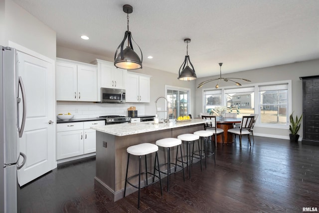 kitchen featuring decorative backsplash, a breakfast bar area, dark wood-style flooring, stainless steel appliances, and a sink