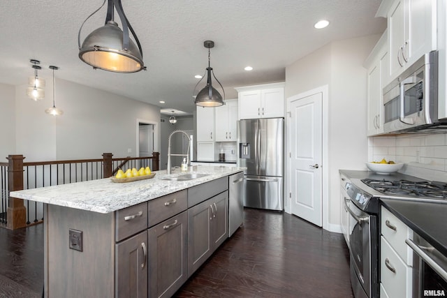 kitchen with dark wood-type flooring, a sink, white cabinets, appliances with stainless steel finishes, and tasteful backsplash