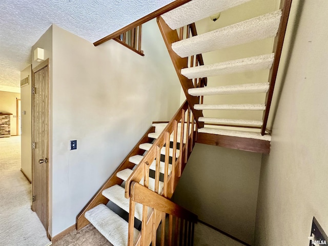 staircase featuring a textured ceiling, visible vents, and baseboards