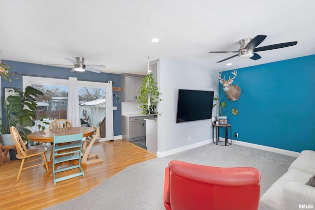 living room featuring light wood-style floors, baseboards, and a ceiling fan