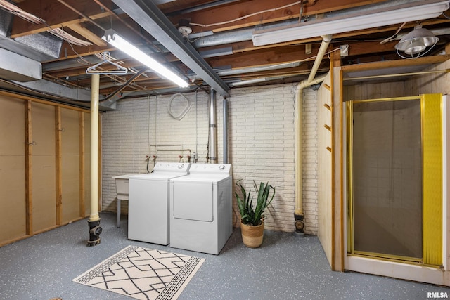 unfinished basement with brick wall and washing machine and dryer