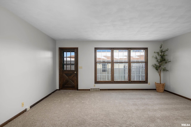 empty room featuring baseboards, visible vents, and light colored carpet