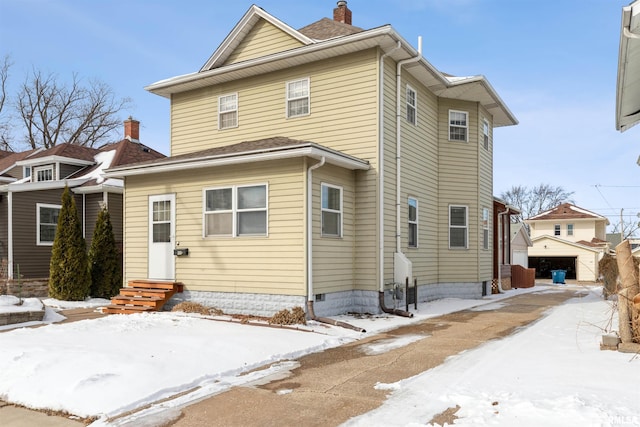 snow covered property featuring entry steps and a detached garage