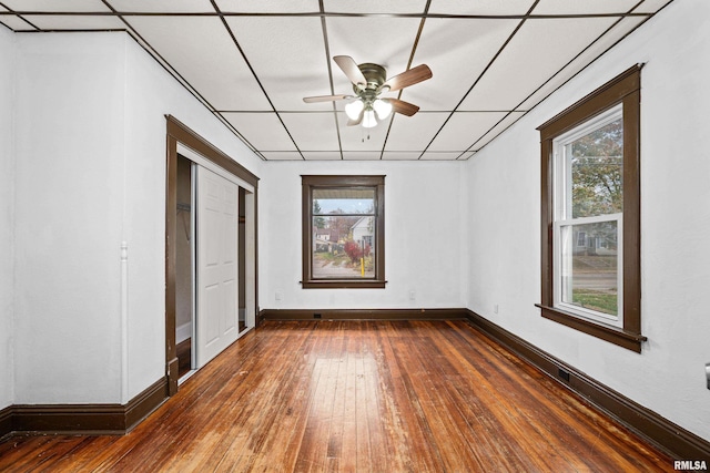 unfurnished room featuring dark wood-style floors, a healthy amount of sunlight, baseboards, and a ceiling fan