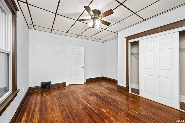 unfurnished bedroom featuring a paneled ceiling, a closet, dark wood finished floors, and visible vents