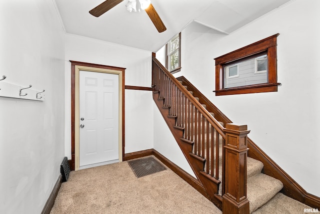 foyer with baseboards, a ceiling fan, ornamental molding, stairs, and carpet flooring