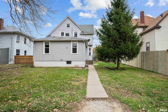 rear view of house with fence private yard and a lawn