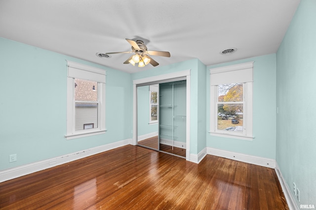 unfurnished bedroom featuring baseboards, a closet, visible vents, and wood finished floors