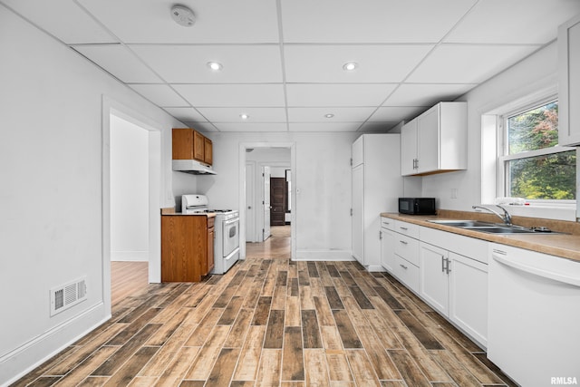 kitchen featuring light countertops, white cabinets, a sink, white appliances, and under cabinet range hood