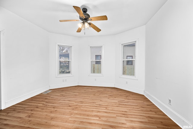spare room with light wood finished floors, ceiling fan, and baseboards