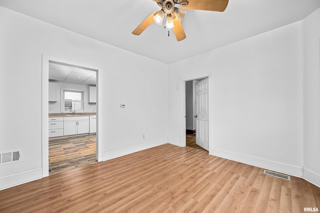 spare room featuring baseboards, visible vents, and light wood-style floors