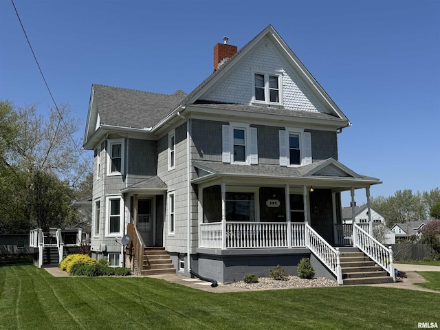 view of front facade with a porch, a front lawn, a shingled roof, and a chimney