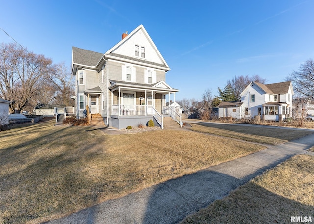 view of front of home with a front yard, covered porch, and a chimney