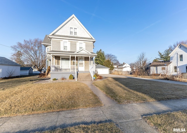 view of front facade featuring a detached garage, an outbuilding, a porch, and a front lawn