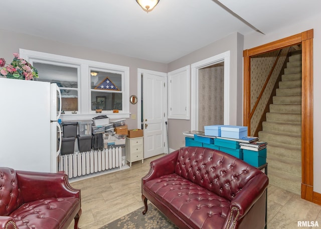 living area featuring stairway and radiator