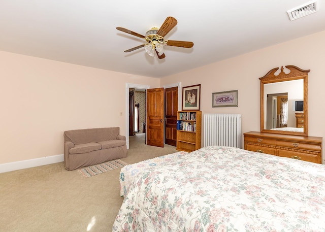 bedroom with a ceiling fan, visible vents, radiator heating unit, baseboards, and light colored carpet