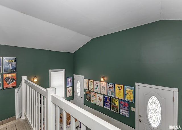hallway with an upstairs landing, wood finished floors, and vaulted ceiling